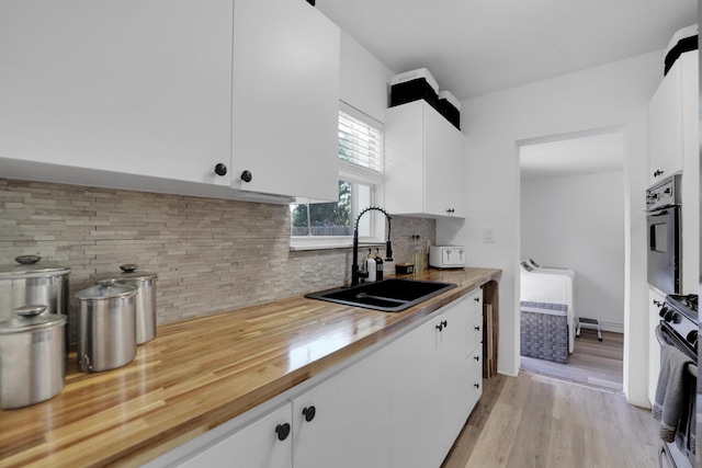 2626 Garfield St, Hollywood, FL 33020 - kitchen with stove, backsplash, light wood-style floors, and white cabinetry