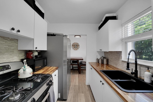 2626 Garfield St, Hollywood, FL 33020 - kitchen with stainless steel gas range, butcher block countertops, black microwave, and white cabinets