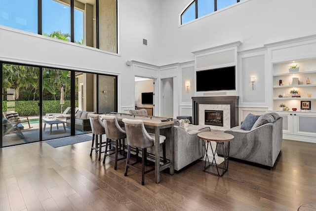 8199 Lost Creek Ln, Delray Beach, FL 33446 - living area featuring a high ceiling, built in shelves, dark wood-style floors, a glass covered fireplace, and a decorative wall