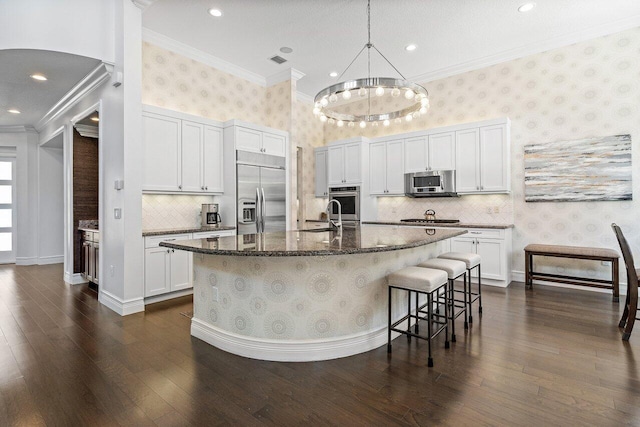 8199 Lost Creek Ln, Delray Beach, FL 33446 - kitchen featuring stainless steel appliances, wallpapered walls, ornamental molding, dark wood-style flooring, and an island with sink