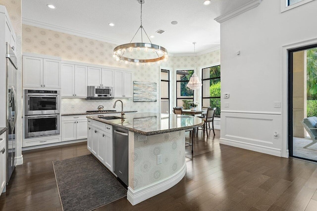 8199 Lost Creek Ln, Delray Beach, FL 33446 - kitchen featuring wallpapered walls, stainless steel appliances, ornamental molding, a kitchen island with sink, and white cabinetry