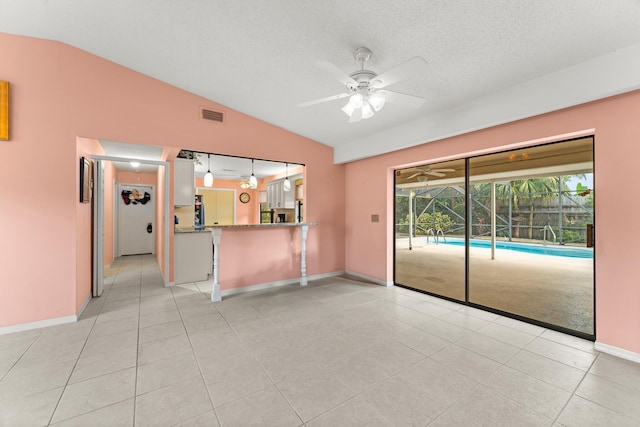 1107 SE Cambridge Dr, Port Saint Lucie, FL 34952 - unfurnished living room with lofted ceiling, a ceiling fan, light tile patterned flooring, and a textured ceiling