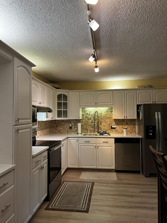 505 5th Ter, Palm Beach Gardens, FL 33418 - kitchen featuring appliances with stainless steel finishes, a textured ceiling, decorative backsplash, light countertops, and glass insert cabinets