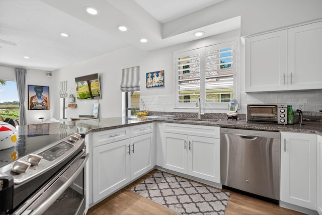31 Dunbar Rd, Palm Beach Gardens, FL 33418 - kitchen with appliances with stainless steel finishes, recessed lighting, decorative backsplash, light wood finished floors, and white cabinetry