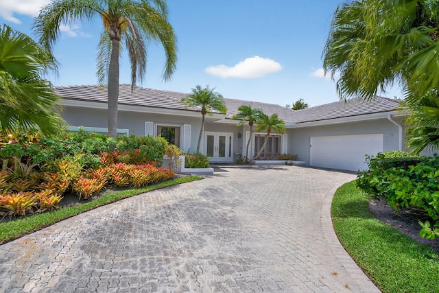 31 Dunbar Rd, Palm Beach Gardens, FL 33418 - ranch-style house with french doors, an attached garage, stucco siding, and a tiled roof
