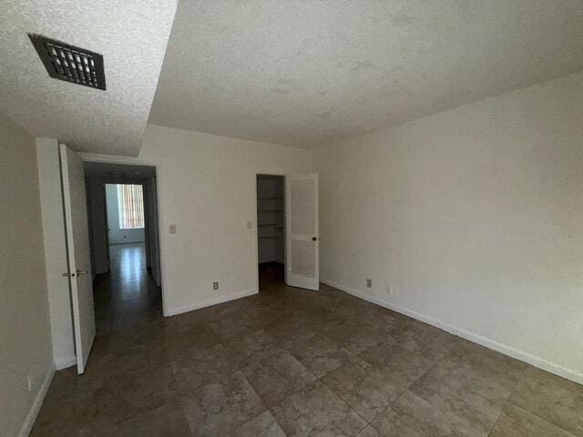 3510 Oaks Way Unit 103, Pompano Beach, FL 33069 - unfurnished bedroom featuring baseboards and a textured ceiling