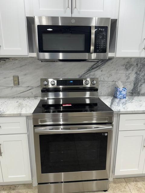 3510 Oaks Way Unit 103, Pompano Beach, FL 33069 - kitchen with stainless steel appliances, white cabinetry, and backsplash