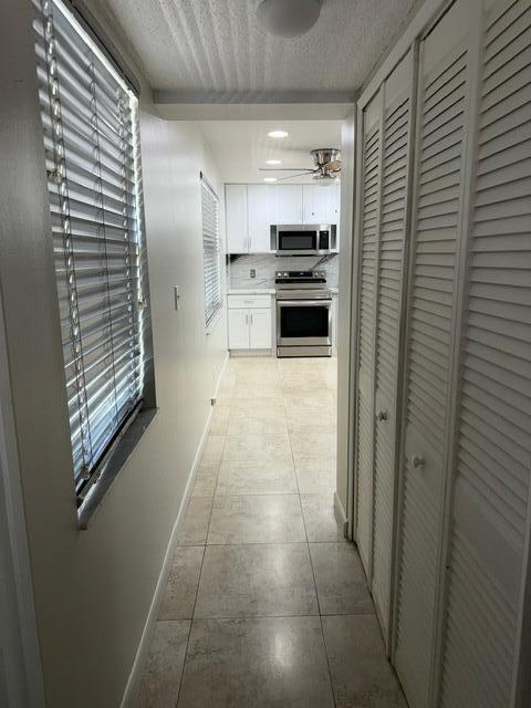 3510 Oaks Way Unit 103, Pompano Beach, FL 33069 - hall with light tile patterned flooring and a textured ceiling