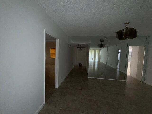 3510 Oaks Way Unit 103, Pompano Beach, FL 33069 - corridor with a textured ceiling and baseboards