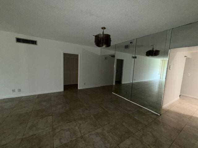 3510 Oaks Way Unit 103, Pompano Beach, FL 33069 - unfurnished bedroom featuring baseboards and a textured ceiling