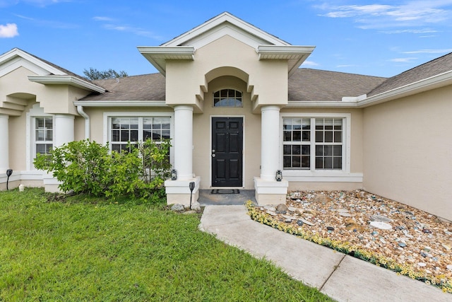 397 SW Jeanne Ave, Port Saint Lucie, FL 34953 - entrance to property featuring stucco siding, a shingled roof, and a lawn