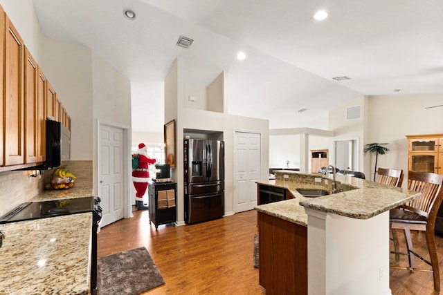 397 SW Jeanne Ave, Port Saint Lucie, FL 34953 - kitchen with stainless steel fridge, a breakfast bar, high vaulted ceiling, decorative backsplash, and brown cabinets