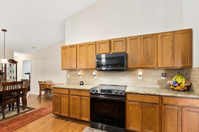 397 SW Jeanne Ave, Port Saint Lucie, FL 34953 - kitchen with electric stove, wood finished floors, decorative backsplash, brown cabinetry, and high vaulted ceiling