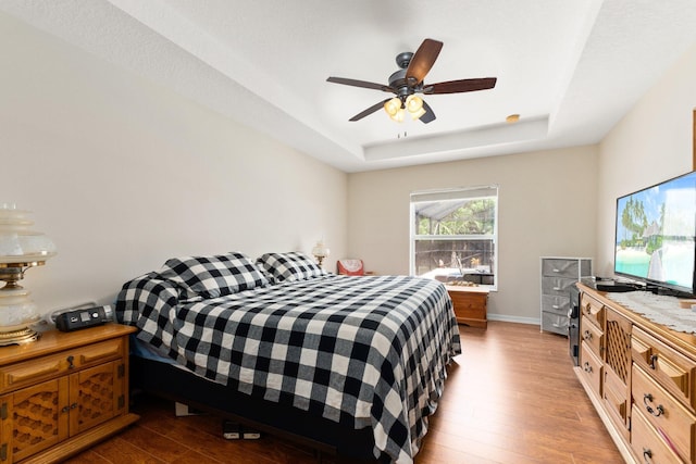 397 SW Jeanne Ave, Port Saint Lucie, FL 34953 - bedroom featuring a tray ceiling, wood finished floors, and a ceiling fan