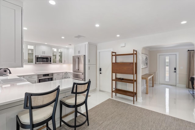 910 SW 21st St, Boca Raton, FL 33486 - kitchen featuring stainless steel appliances, glass insert cabinets, light countertops, a breakfast bar, and arched walkways