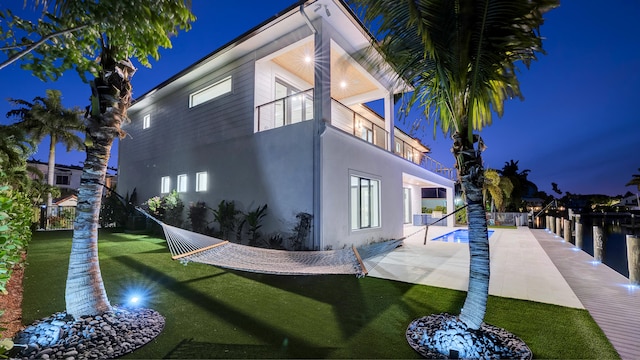 811 Chukker Rd, Delray Beach, FL 33483 - property exterior at twilight with stucco siding, a patio, a balcony, and a yard