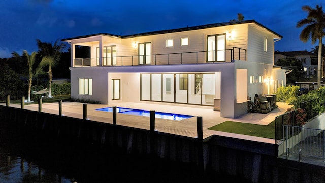 811 Chukker Rd, Delray Beach, FL 33483 - back of house at night featuring a balcony, a patio area, and stucco siding