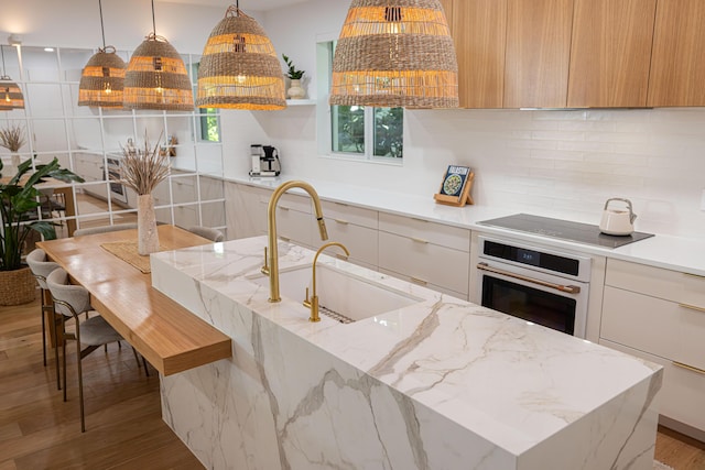 3245 Wymberly Dr, Jupiter, FL 33458 - kitchen featuring oven, modern cabinets, black electric stovetop, decorative backsplash, and light wood-style flooring