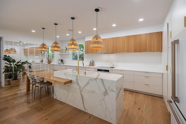 3245 Wymberly Dr, Jupiter, FL 33458 - kitchen with modern cabinets, light wood-style floors, a kitchen island with sink, recessed lighting, and decorative light fixtures