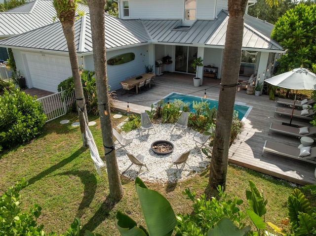 3245 Wymberly Dr, Jupiter, FL 33458 - back of house with a standing seam roof, a metal roof, a deck, a fire pit, and a garage