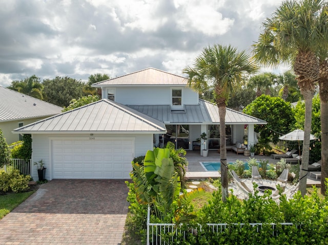 3245 Wymberly Dr, Jupiter, FL 33458 - rear view of house featuring a standing seam roof, a metal roof, decorative driveway, and a garage