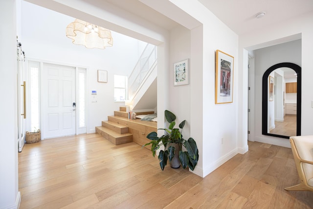 3245 Wymberly Dr, Jupiter, FL 33458 - entrance foyer with light wood-style floors, stairs, arched walkways, a chandelier, and a barn door