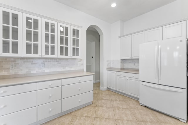 918 SW Blue Stem Way, Stuart, FL 34997 - kitchen featuring freestanding refrigerator, arched walkways, light countertops, glass insert cabinets, and backsplash