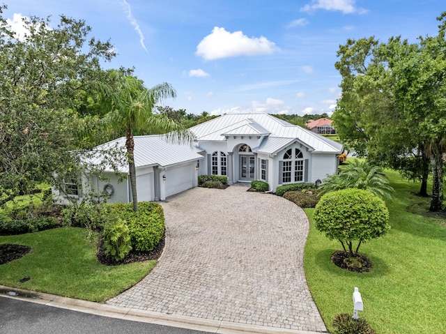 918 SW Blue Stem Way, Stuart, FL 34997 - view of front of property featuring french doors, a standing seam roof, an attached garage, decorative driveway, and stucco siding