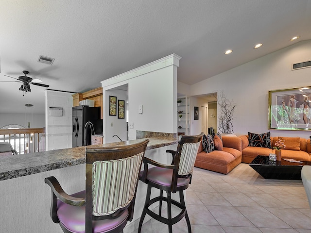 10828 Lake Palm Ln Unit 202, Boynton Beach, FL 33437 - kitchen with black fridge, ceiling fan, a kitchen bar, vaulted ceiling, and light tile patterned floors