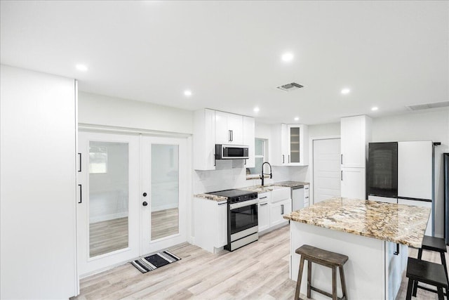 673 NE Horizon Ln, Port Saint Lucie, FL 34983 - kitchen with appliances with stainless steel finishes, a kitchen breakfast bar, light stone counters, french doors, and a center island