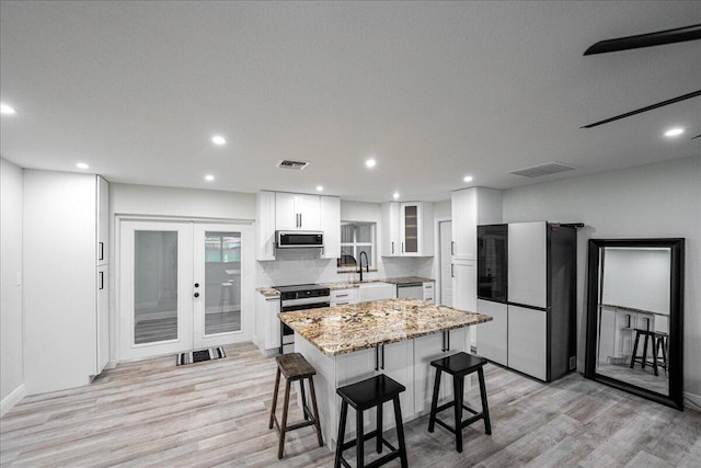 673 NE Horizon Ln, Port Saint Lucie, FL 34983 - kitchen featuring appliances with stainless steel finishes, a kitchen bar, light wood-style flooring, white cabinets, and recessed lighting