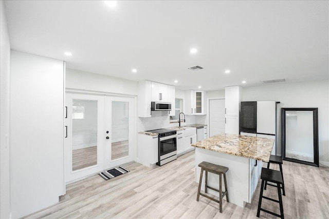 673 NE Horizon Ln, Port Saint Lucie, FL 34983 - kitchen featuring stainless steel appliances, a kitchen breakfast bar, french doors, white cabinetry, and recessed lighting