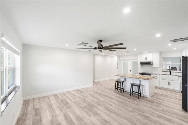 673 NE Horizon Ln, Port Saint Lucie, FL 34983 - kitchen with a kitchen island, a kitchen bar, white cabinets, range, and light wood finished floors