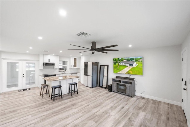 673 NE Horizon Ln, Port Saint Lucie, FL 34983 - kitchen with freestanding refrigerator, stainless steel microwave, a center island, a kitchen breakfast bar, and white cabinetry
