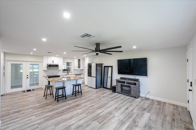 673 NE Horizon Ln, Port Saint Lucie, FL 34983 - kitchen with freestanding refrigerator, stainless steel microwave, a kitchen island, a kitchen breakfast bar, and recessed lighting