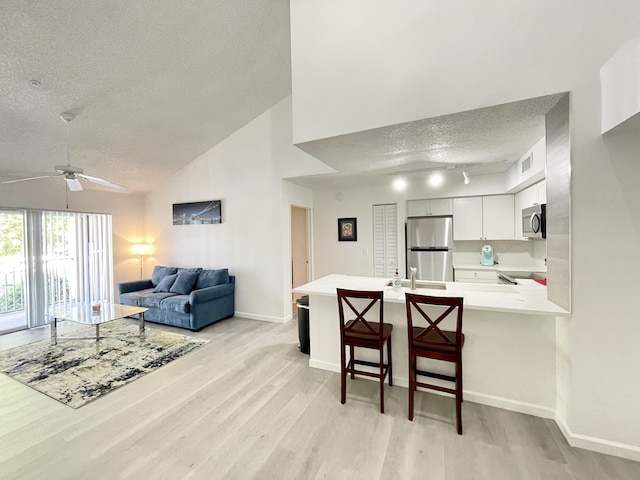 7832 Sonoma Springs Cir Unit 203, Lake Worth, FL 33463 - kitchen featuring stainless steel appliances, a textured ceiling, a peninsula, light wood-style flooring, and ceiling fan