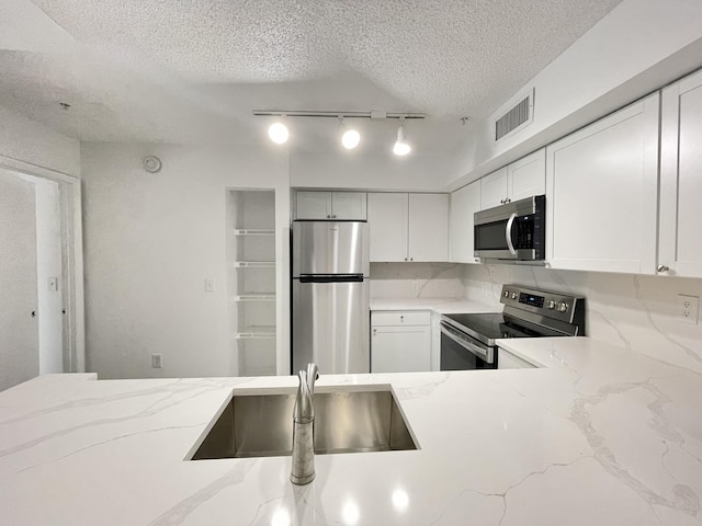 7832 Sonoma Springs Cir Unit 203, Lake Worth, FL 33463 - kitchen featuring stainless steel appliances, a textured ceiling, white cabinets, light stone counters, and rail lighting