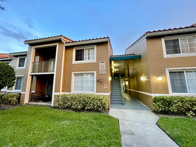 7832 Sonoma Springs Cir Unit 203, Lake Worth, FL 33463 - view of property with stucco siding, a tiled roof, a front lawn, and a balcony