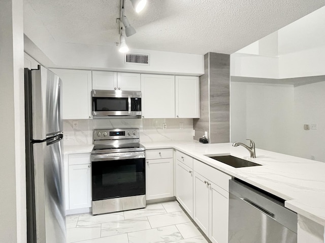 7832 Sonoma Springs Cir Unit 203, Lake Worth, FL 33463 - kitchen with appliances with stainless steel finishes, light marble finish flooring, light stone countertops, white cabinetry, and a textured ceiling