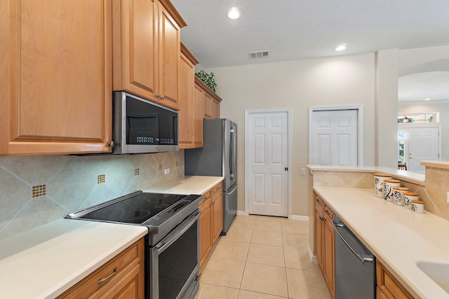 5885 SE Forest Glade Trl, Hobe Sound, FL 33455 - kitchen with appliances with stainless steel finishes, backsplash, light tile patterned flooring, light countertops, and arched walkways