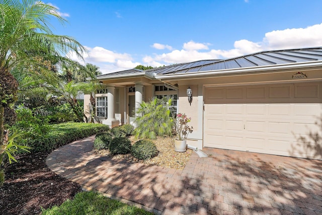 5885 SE Forest Glade Trl, Hobe Sound, FL 33455 - view of front facade with a standing seam roof, stucco siding, a metal roof, an attached garage, and decorative driveway