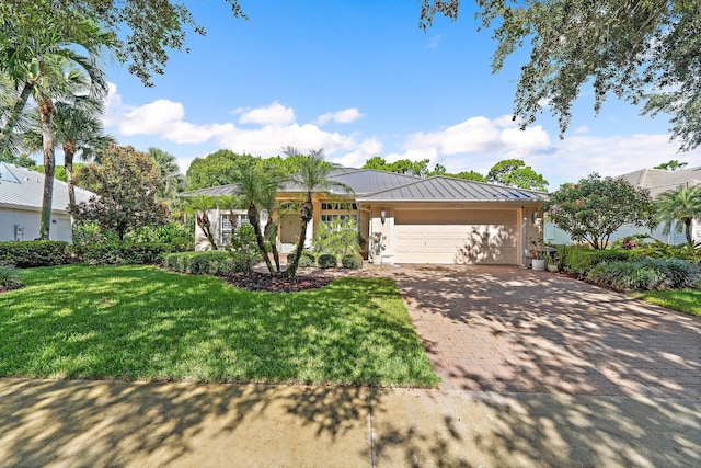 5885 SE Forest Glade Trl, Hobe Sound, FL 33455 - ranch-style home with a standing seam roof, an attached garage, a metal roof, a front lawn, and decorative driveway