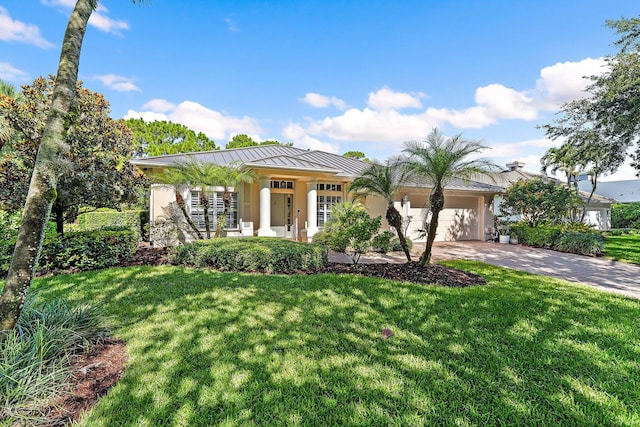 5885 SE Forest Glade Trl, Hobe Sound, FL 33455 - view of front of property with a standing seam roof, driveway, an attached garage, and a front lawn