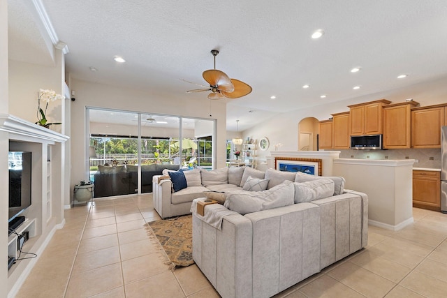 5885 SE Forest Glade Trl, Hobe Sound, FL 33455 - living room with light tile patterned floors, ceiling fan, recessed lighting, a glass covered fireplace, and arched walkways