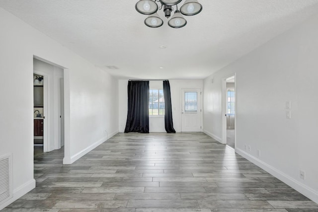 1669 SE N Blackwell Dr, Port Saint Lucie, FL 34952 - unfurnished room featuring a chandelier, wood finished floors, and a textured ceiling