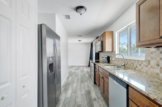 1669 SE N Blackwell Dr, Port Saint Lucie, FL 34952 - kitchen with appliances with stainless steel finishes, light wood-style flooring, brown cabinetry, and a textured ceiling