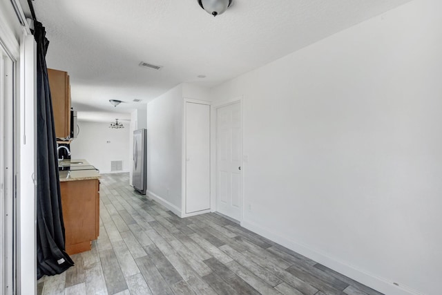 1669 SE N Blackwell Dr, Port Saint Lucie, FL 34952 - kitchen with freestanding refrigerator, light wood-type flooring, a textured ceiling, and brown cabinets