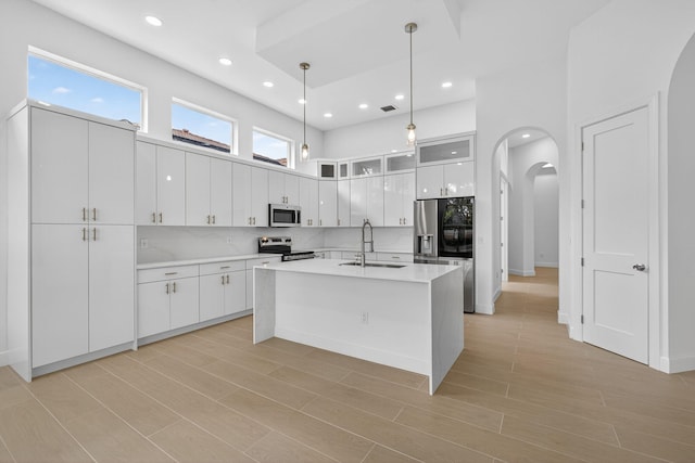 8873 Via Brilliante, Wellington, FL 33411 - kitchen featuring appliances with stainless steel finishes, arched walkways, white cabinetry, hanging light fixtures, and recessed lighting