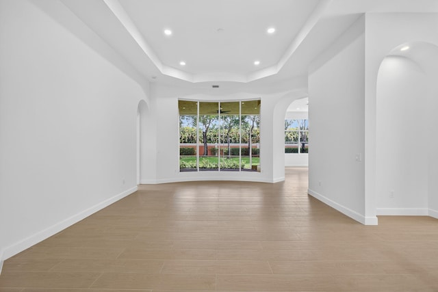 8873 Via Brilliante, Wellington, FL 33411 - empty room with arched walkways, recessed lighting, a raised ceiling, and wood finished floors
