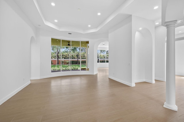 8873 Via Brilliante, Wellington, FL 33411 - unfurnished living room featuring recessed lighting, arched walkways, a tray ceiling, and light wood-style floors